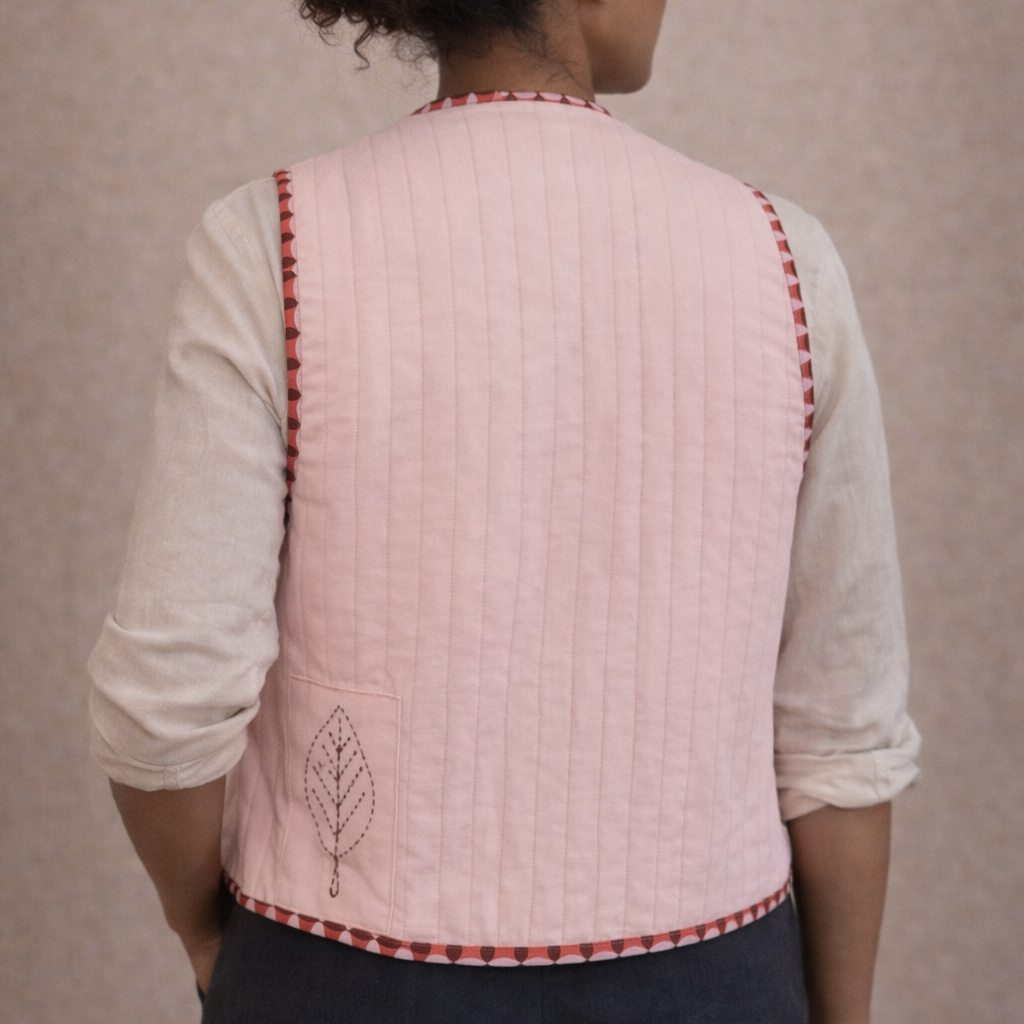 Woman wearing a pink quilted vest with red trim against a beige background