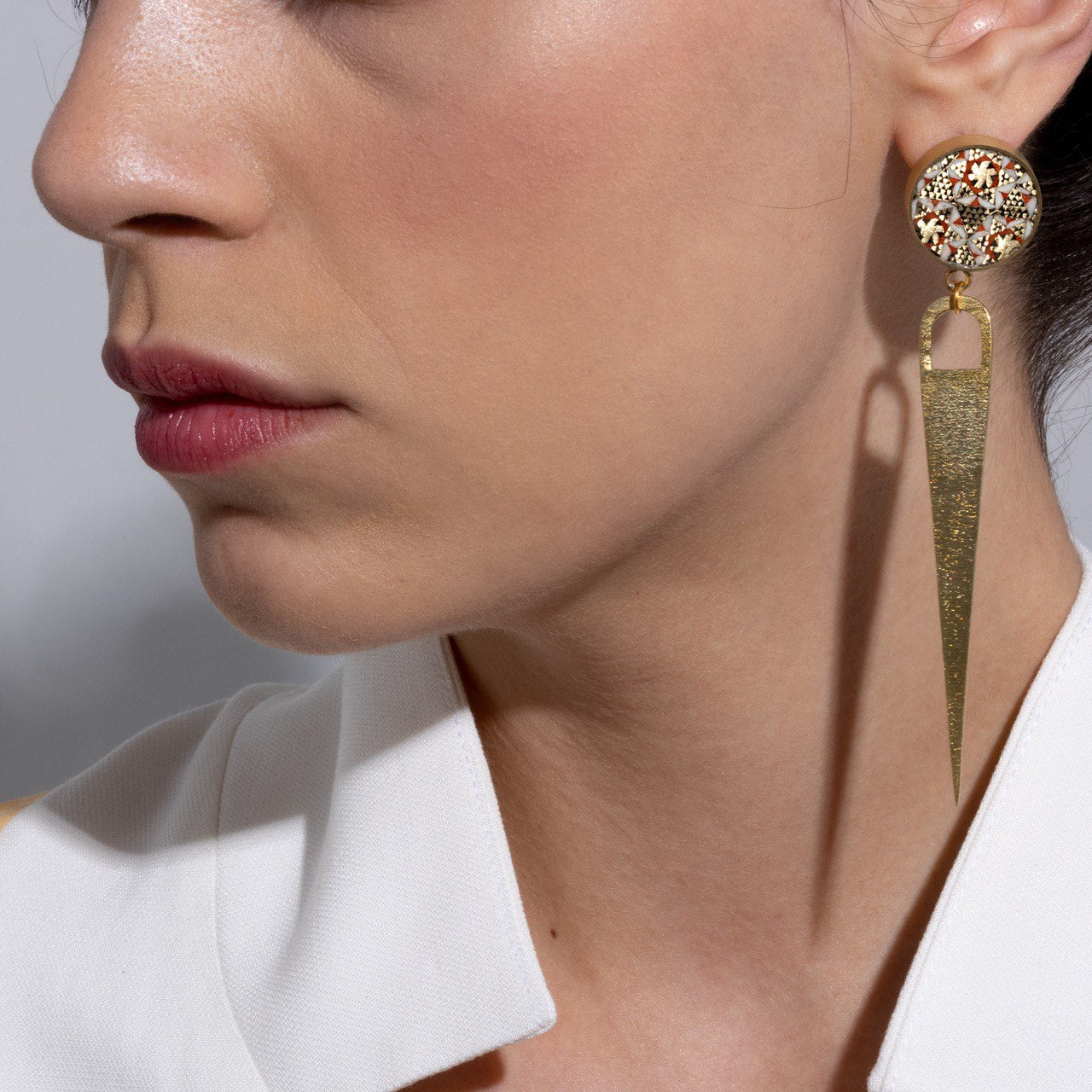 Pair of earrings with turquoise teardrop shapes and decorative tops on a beige background